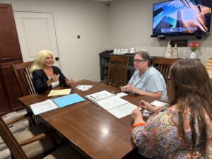 Blog Three people in a meeting at Precision Retirement and Benefits LLC discussing plans around a conference table.